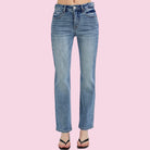 Blue jeans on a person against a pink background