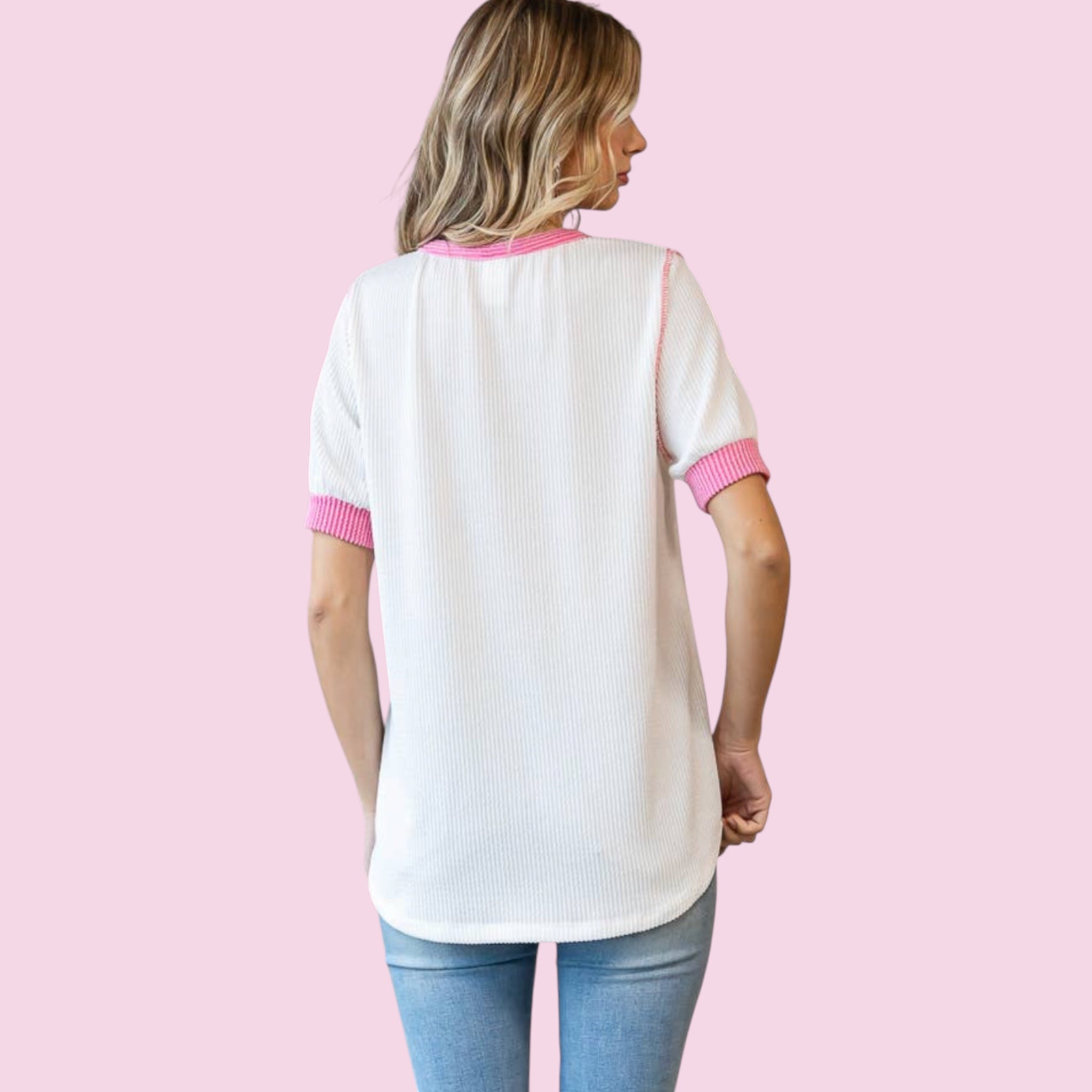 Woman wearing a white and pink baseball-style shirt on a pink background