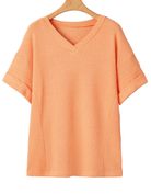 Orange textured t-shirt on a hanger against a light gray background