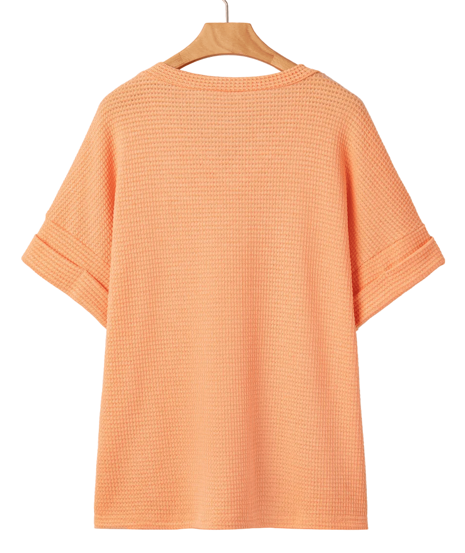 Orange textured t-shirt on a hanger against a white background