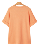Orange textured t-shirt on a hanger against a white background