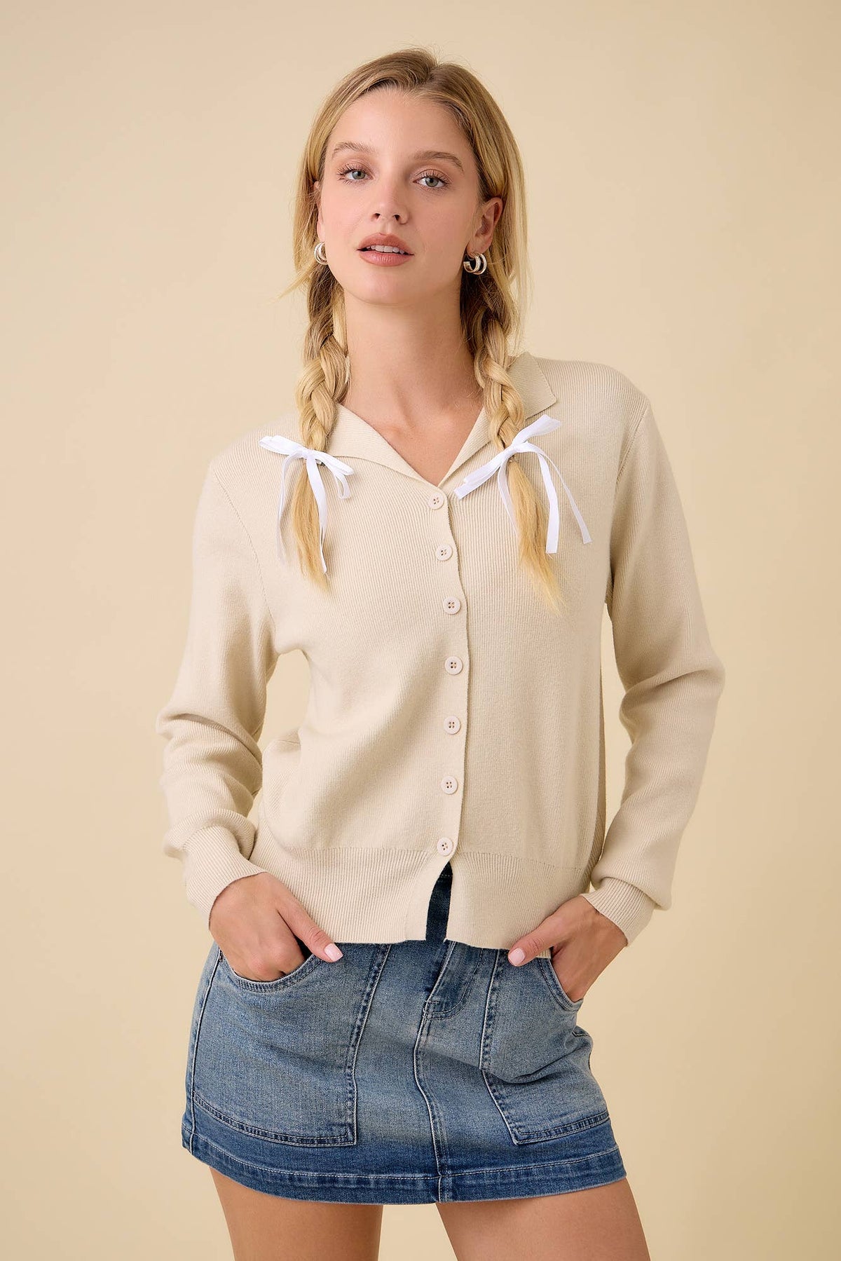 Front view of the natural collared sweater cardigan styled with a denim mini skirt