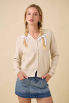 Front view of the natural collared sweater cardigan styled with a denim mini skirt