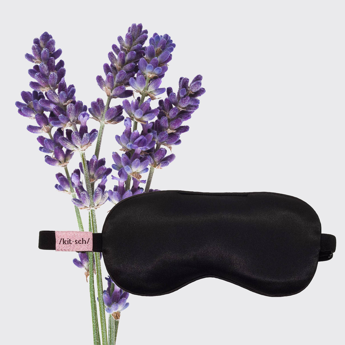 KITSCH black satin weighted eye mask next to fresh lavender sprigs