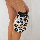 Leopard print Kitsch exfoliating glove being used on a leg
