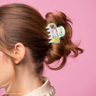 Lisa Frank Markie unicorn claw clip holding a messy bun in brown hair