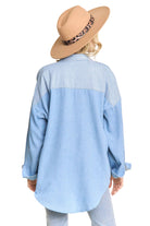 Person wearing a light blue denim shirt and a beige hat with a leopard print band on a beige background