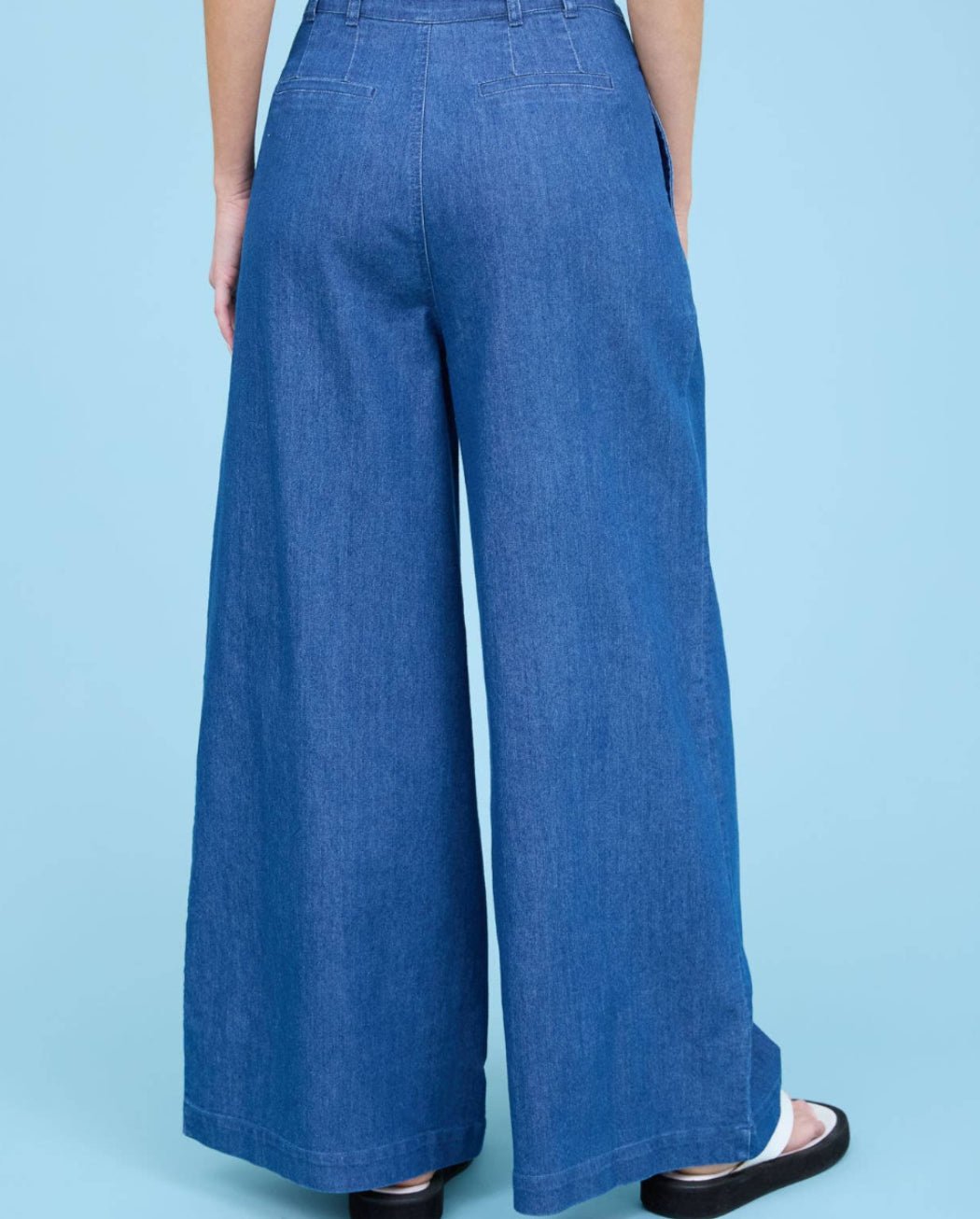 Person wearing blue wide-leg pants on a light blue background