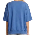 Person wearing a blue oversized t-shirt and denim shorts on a white background