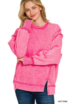 Woman wearing an oversized hot pink acid wash fleece sweatshirt with exposed seams, drop shoulders and side slits, styled with dark wash jeans