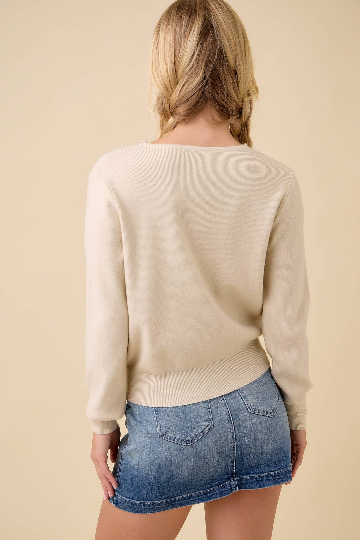 Back view of the cream knit button up cardigan with a denim skirt