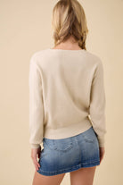 Back view of the cream knit button up cardigan with a denim skirt