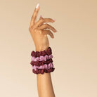 Burgundy and dusty pink lace scrunchies stacked on a wrist