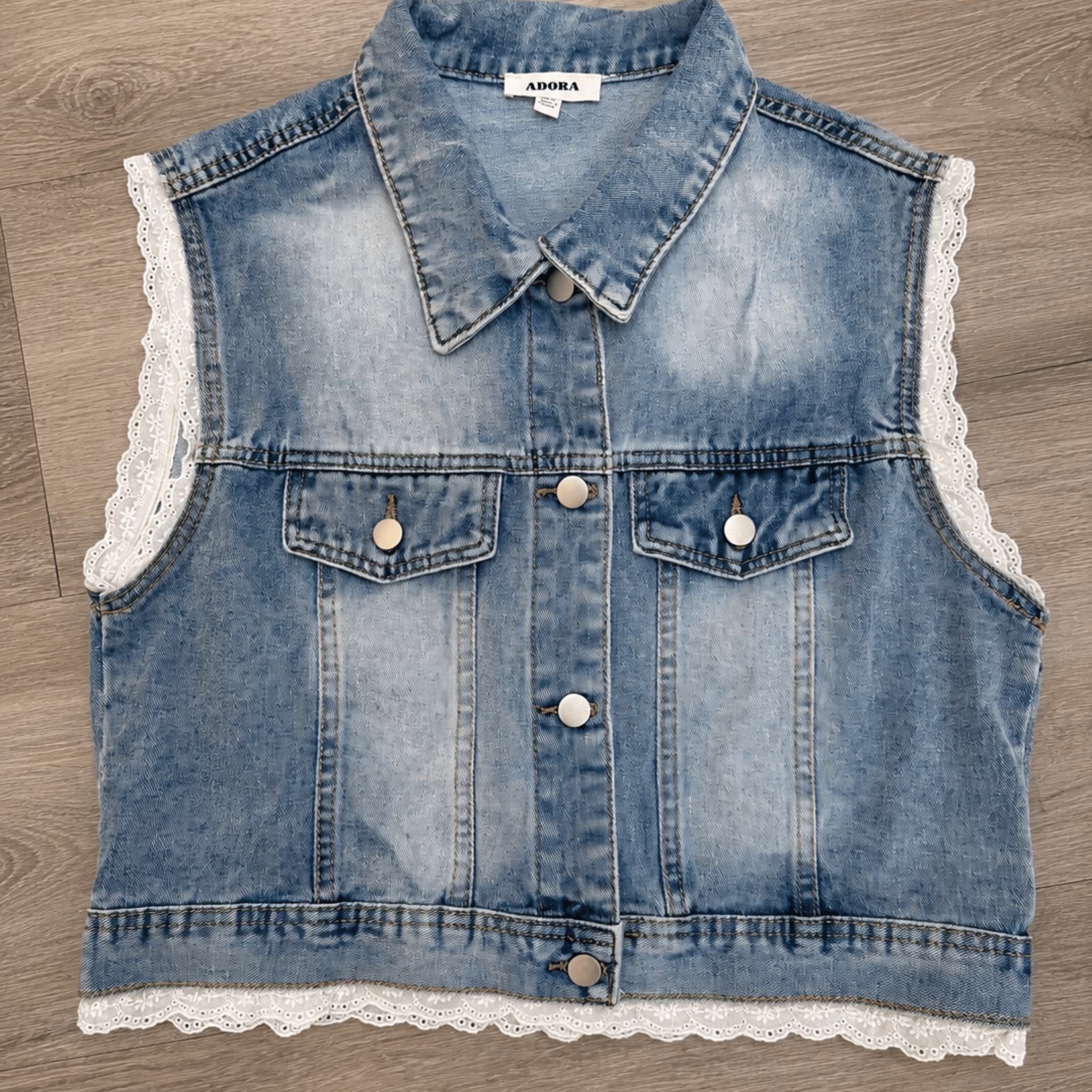 Denim vest with lace trim on a wooden surface