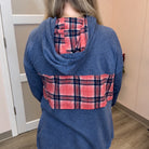 A person shown from the back wearing a heathered blue hooded sweatshirt with a red, navy, and white plaid pattern across the back and a matching plaid lining inside the hood.