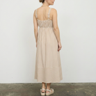 woman standing in a room wearing a beige stripped dress with sandals on 