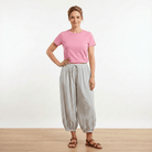 Woman wearing a pink t-shirt and striped pants on a white background