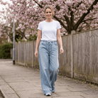 Woman walking outdoors in Judy Blue High Waist Palazzo Featherweight Drawcord Jeans with white top