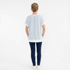 Person wearing a light blue t-shirt and dark blue jeans on a white background