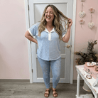 Woman in a striped shirt and jeans standing in a room with pink walls and decorative elements.