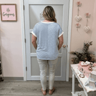Woman standing in a room with decorative elements and a mirror.