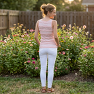 Woman standing in a garden with flowers and a wooden fence in the background