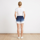 Person wearing a white t-shirt and blue ombre shorts against a plain background