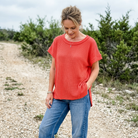 Women wearing red top with denim jeans standing on a gravel road.