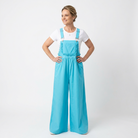 Woman wearing bright blue overalls and a white shirt on a white background