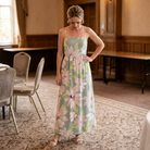 Woman in a floral dress standing in an elegant room with chairs and tables.