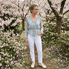 Woman standing in a garden with cherry blossom trees in the background