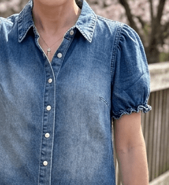 Close-up of puff sleeve denim top with pearl snap buttons