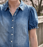 Close-up of puff sleeve denim top with pearl snap buttons