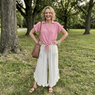 Woman in a pink shirt and white pants standing in a park